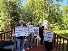 Picture of UNAC negotiaiton team members outside on a deck holding pro-faculty signs